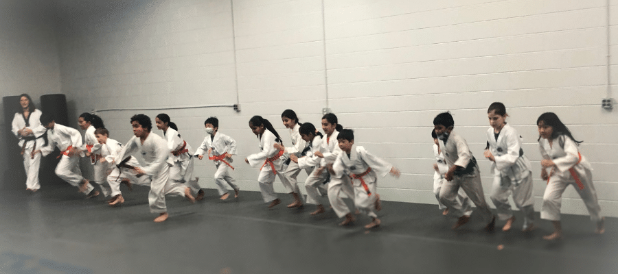 A row of students in martial arts uniforms running at their karate school Akula Taekwondo