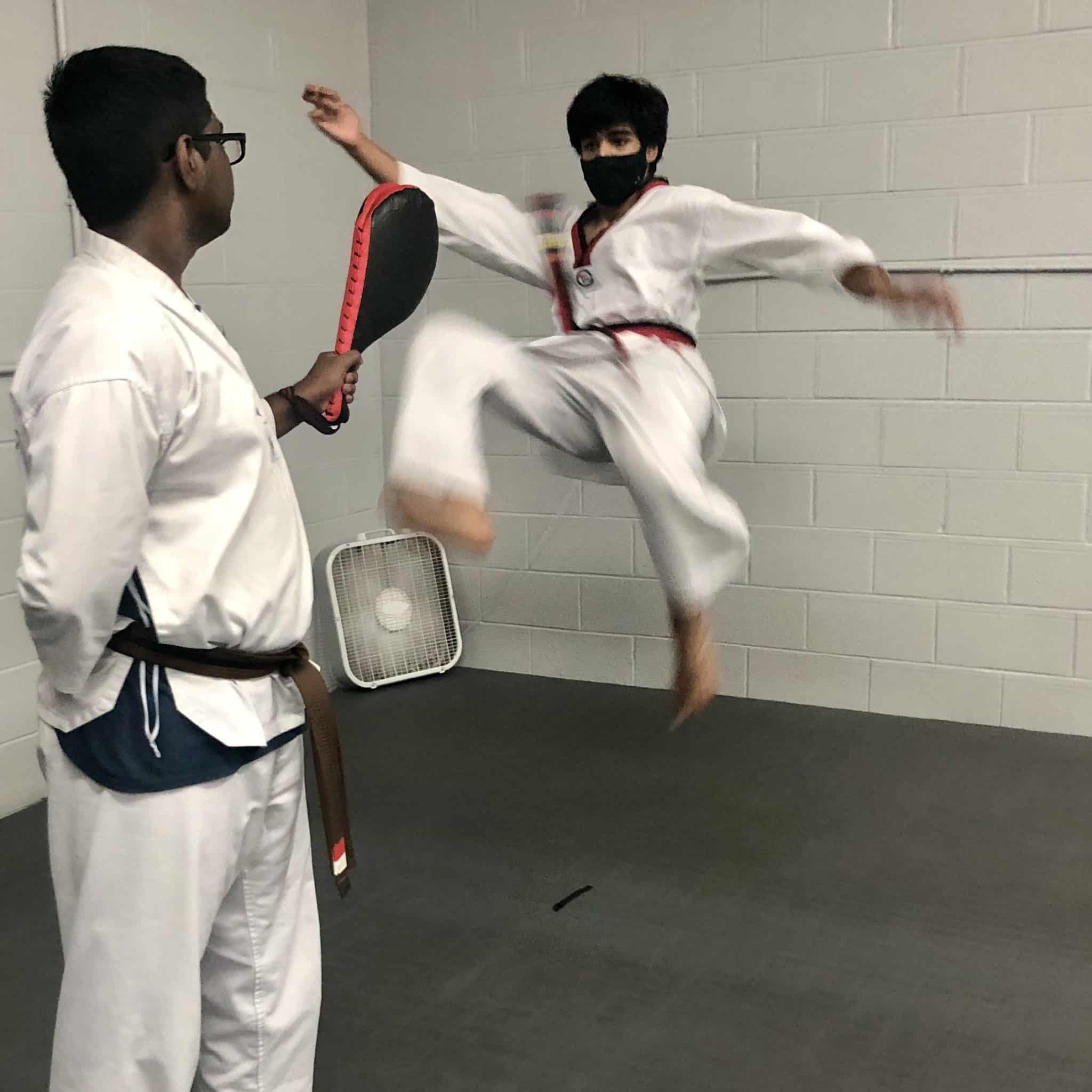 Teen boys in white uniforms practice Taekwondo kicks