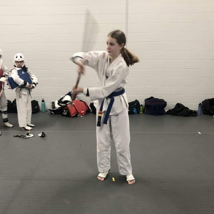 Girl in Taekwondo uniform trains with a Bo staff at Akula Taekwondo Novi MI Karate School