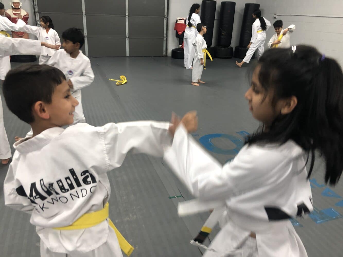 Smiling boy and girl practice self-defense drills at Akula Taekwondo
