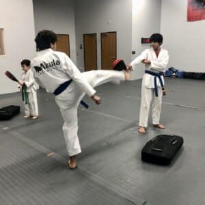 Two teenagers doing a kicking drill at Akula Taekwondo.