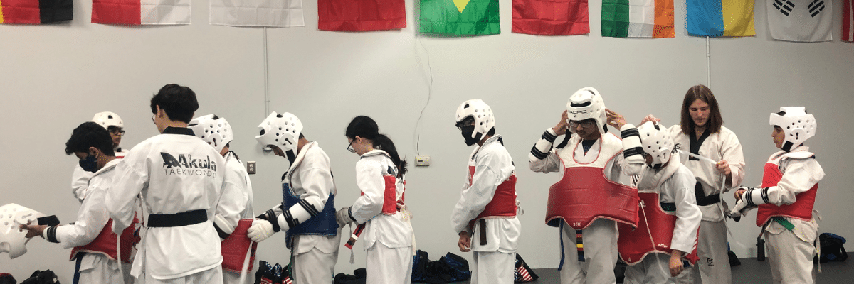 Martial Arts students putting on protective equipment at Akula Taekwondo in Novi, MI