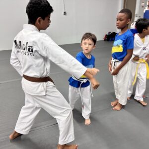 Teen Taekwondo student helps a young martial artist